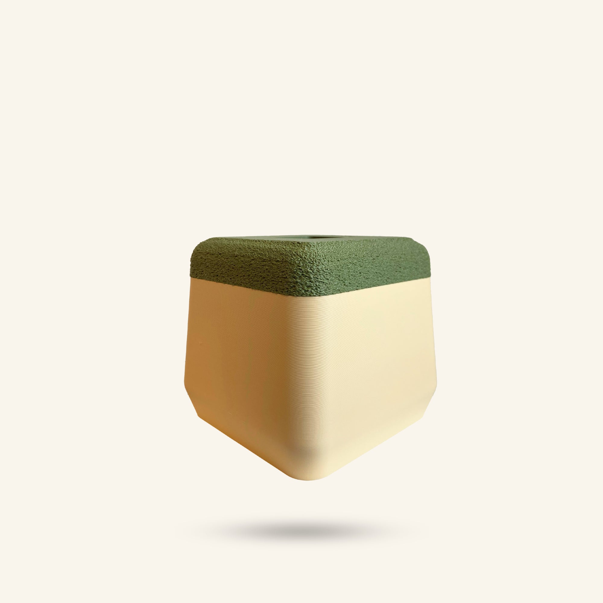 Small, geometric plant pot with a green top and beige bottom on a white background