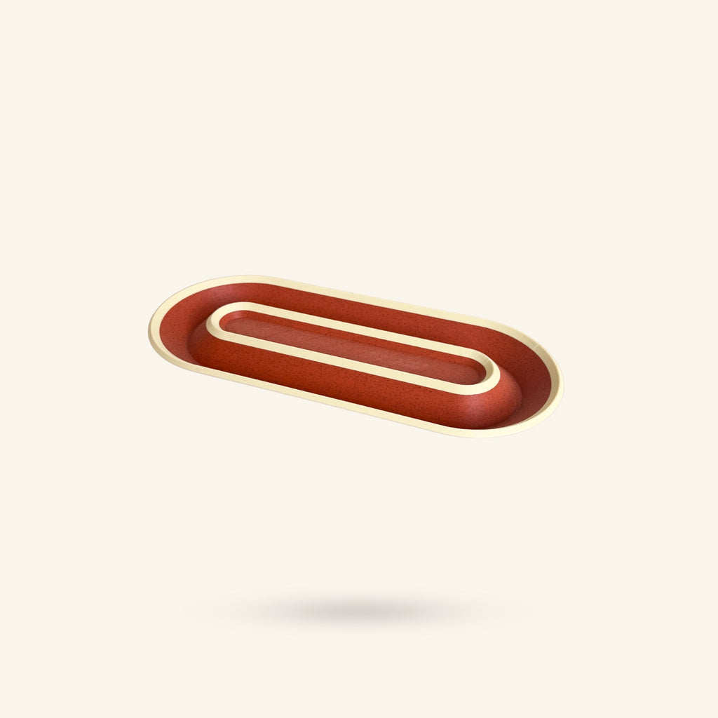 OBJ STUDIO Nook Tray in a 2-tone red and cream plant-based PLA material with a curved, minimalist oval design.
